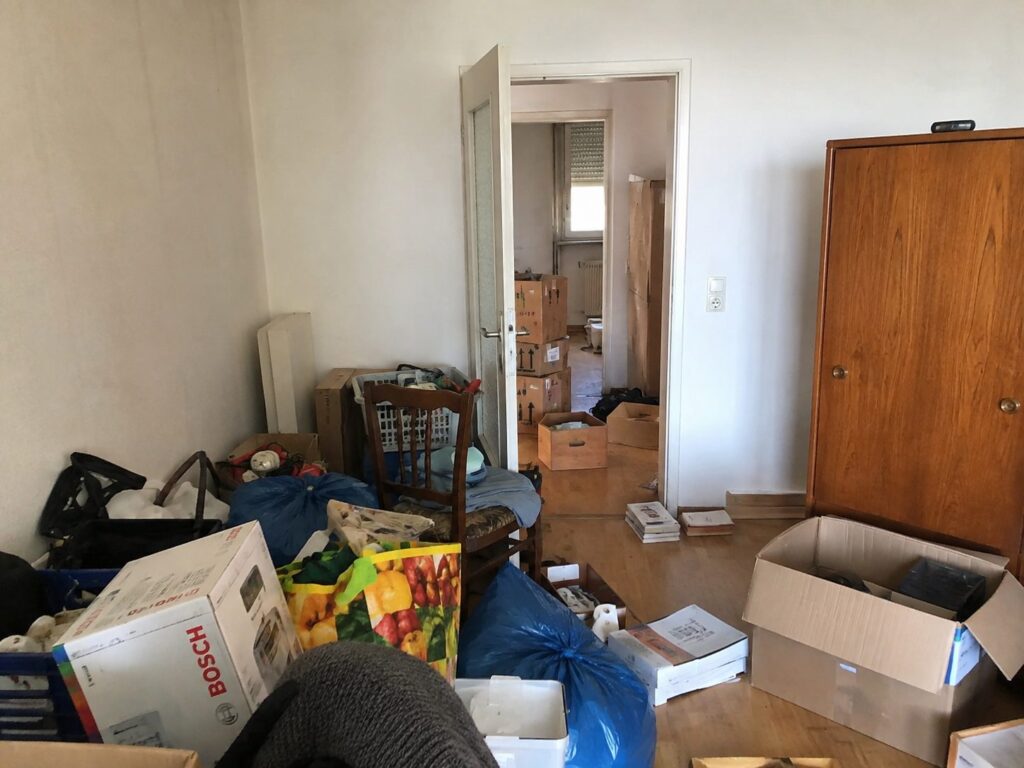 Wohnzimmer voller Kartons, Möbel und Hausrat vor der Räumung